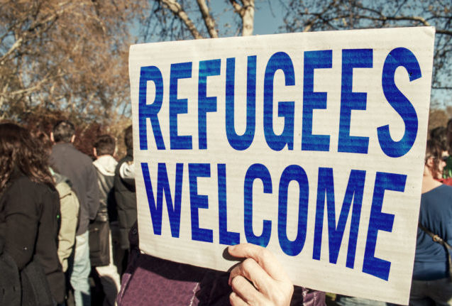 hand holding refugees welcome sign