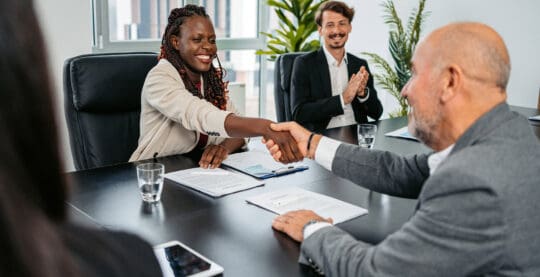Multi-racial employees shaking hands over a table